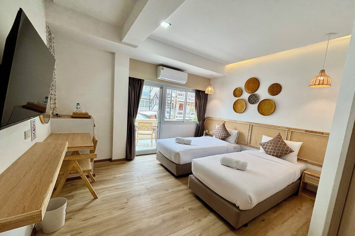 Habitación de hotel con dos camas, un escritorio y un televisor.