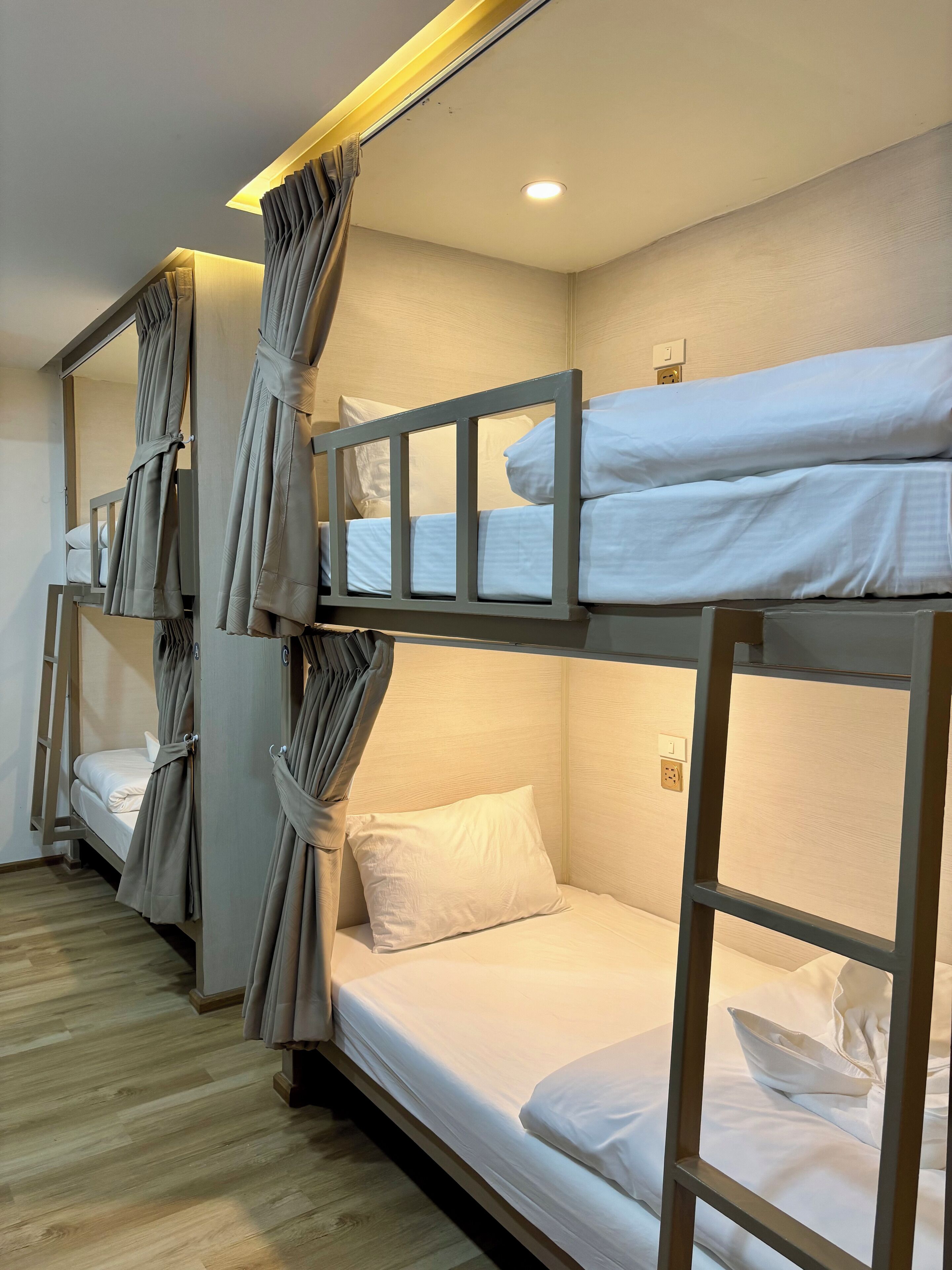 Een hotelkamer met stapelbedden, houten vloeren en gordijnen.