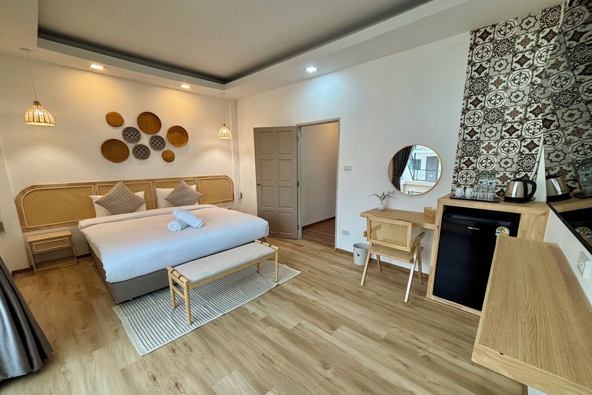 Una habitación de hotel moderna con una cama grande, mesitas de noche, un escritorio y una kitchenette.