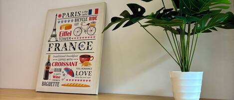 A wooden table with a potted plant and a framed sign about France.