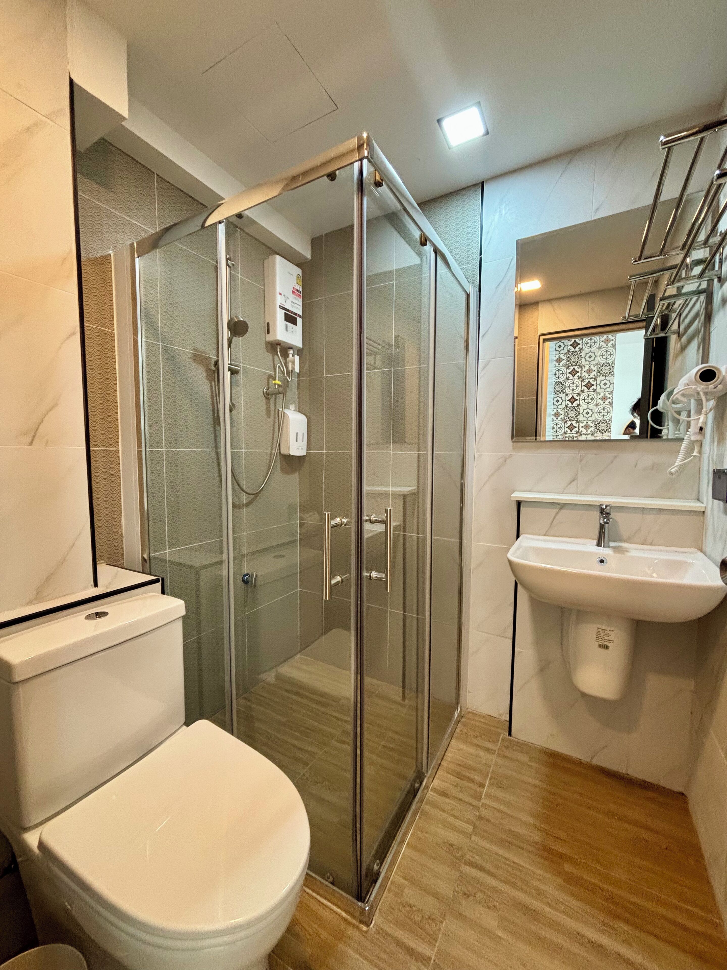 A modern bathroom with a glass-enclosed shower, a white toilet, and a sink.