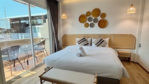 Een moderne hotelkamer met een groot bed, een bank, een zithoek met stoelen en uitzicht op buiten.