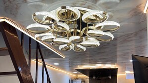 A modern hotel lobby with a marble floor, a reception desk, a staircase, and a chandelier.