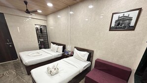 A hotel room with two beds, a sofa, a bathroom with a mirror, and a framed picture on the wall.