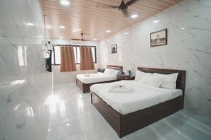 A hotel room with two beds, marble walls, wooden ceiling, and a ceiling fan. - Hotel Jupiter Residency (Mumbai)