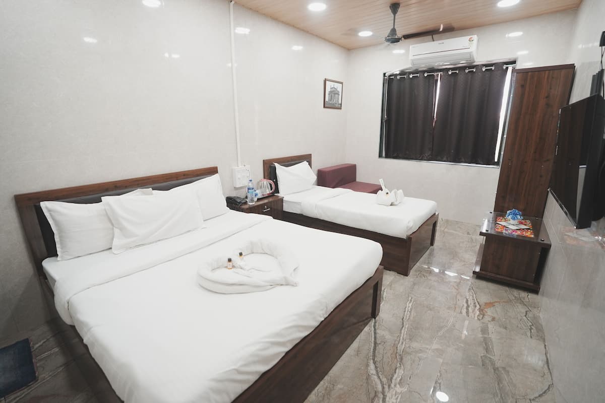 A hotel room with two beds, a wooden headboard, a marble floor, a small table with toiletries, and a window with curtains.