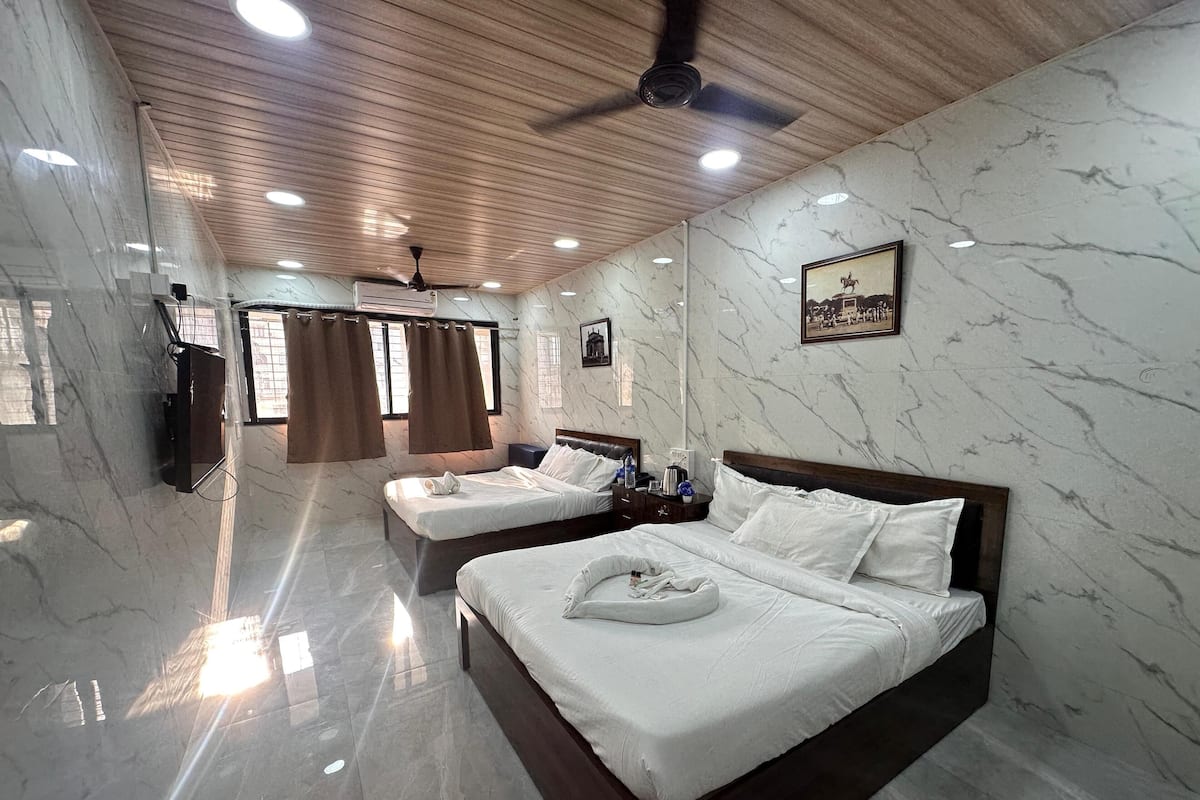 A hotel room with a large bed, a smaller bed, a ceiling fan, and marble walls.