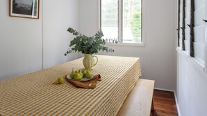 A room with a checkered tablecloth, a vase with green foliage, and a plate of pears.