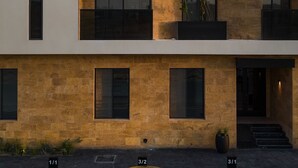 Un immeuble à plusieurs étages doté d’une architecture moderne, avec des balcons ornés de plantes et de grandes fenêtres.