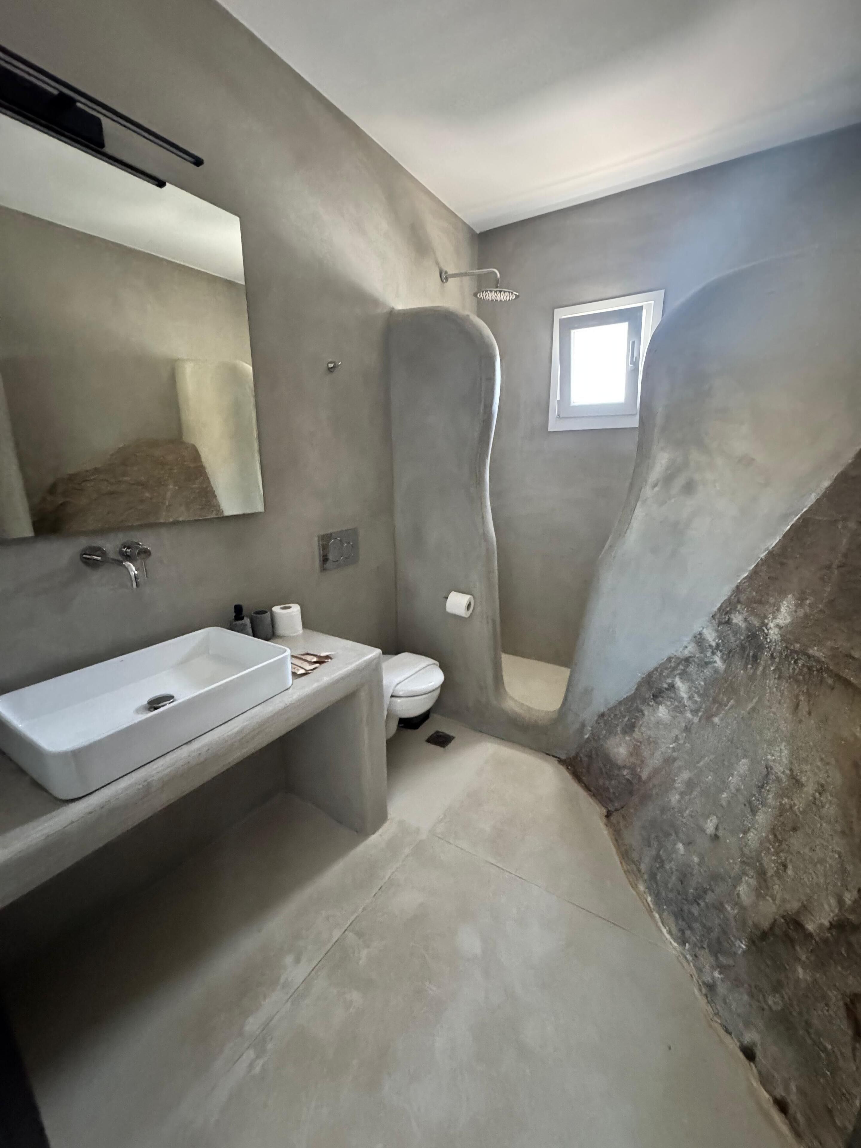 Une salle de bain avec un lavabo, des toilettes et une douche, le tout de couleur blanche.
