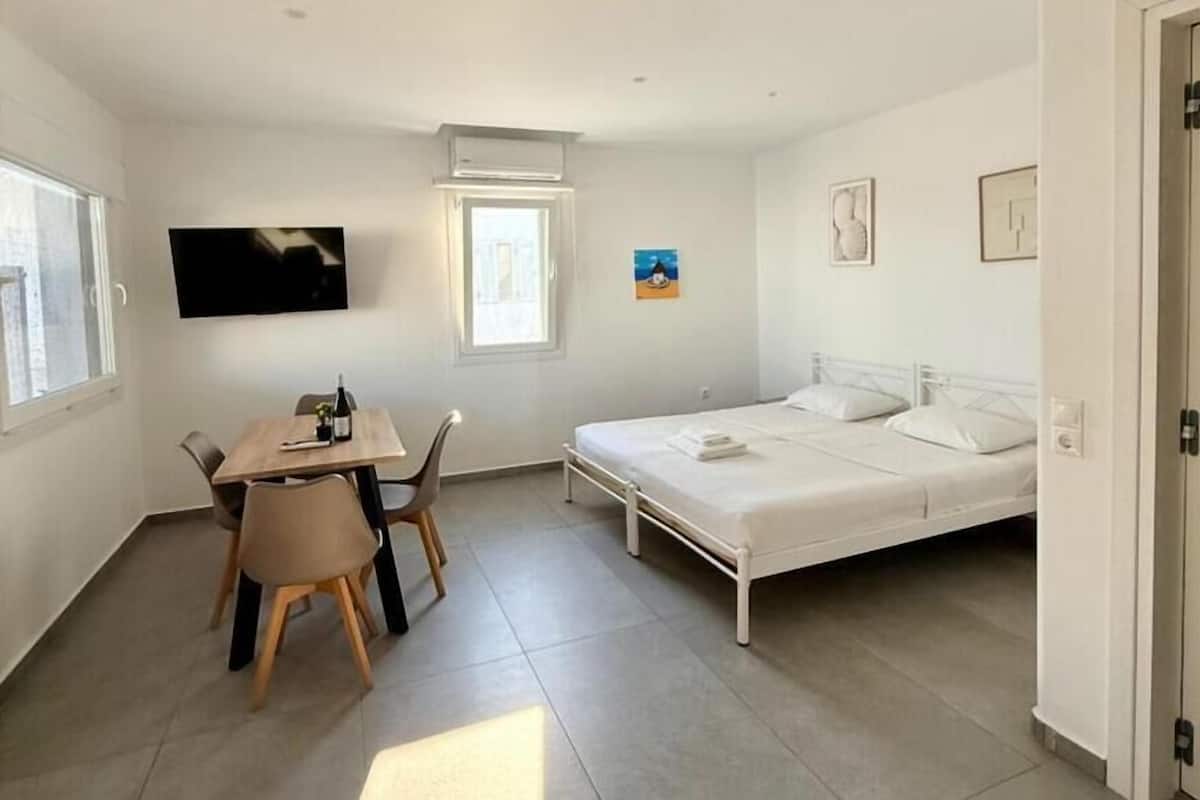 Una habitación pequeña y luminosa con una cama, una mesa y sillas.