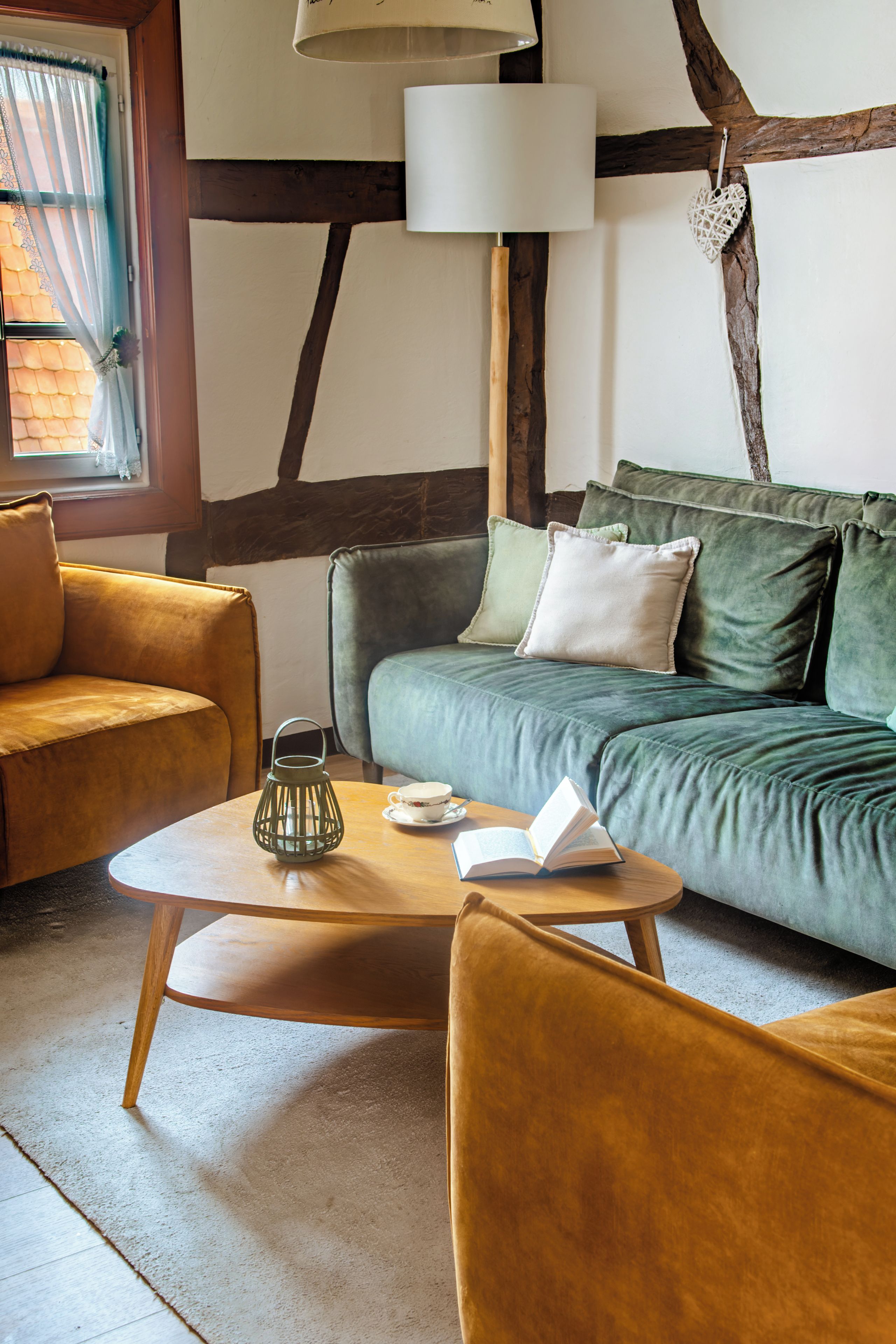 A cozy living room with a wooden coffee table, a green sofa with cushions, and a yellow armchair.