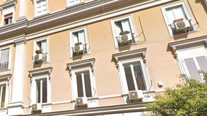 A multi-story building with a classical architectural style, featuring evenly spaced windows and balconies with potted plants. - Matera's Home VB By Dimorra (NAPOLI)