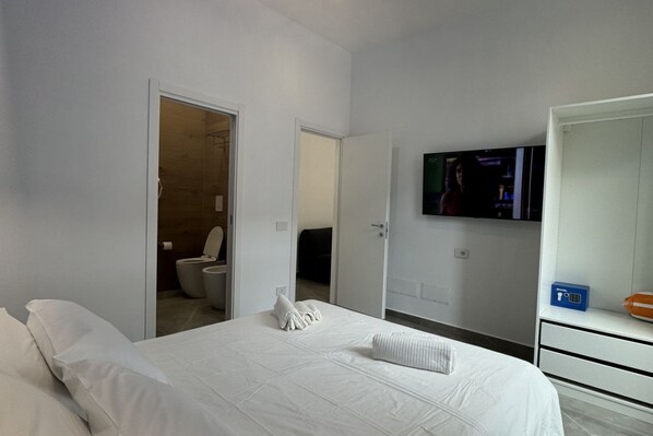 Una habitación de hotel con una cama, un televisor montado en la pared y un armario.