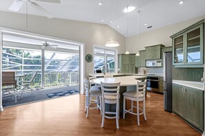 A modern kitchen with a central island, white chairs, and a dining table. - Rabbit Foot Retreat- Reduced Rates For Summer & Fall 2026 (Sanibel)