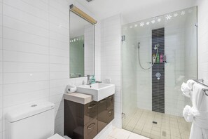 Bathroom features a glass shower enclosure, vertical control panel, and a separate toilet.