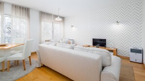 Een moderne woonkamer met een bank, een eettafel met stoelen, een televisie en een wandheater.