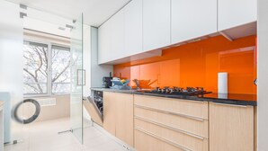 Een moderne keuken met een glazen scheiding, een kookplaat en een raam met uitzicht op bomen.