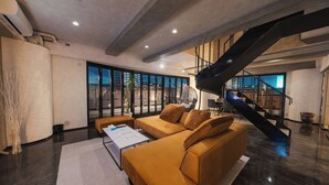 Ein modernes Wohnzimmer mit einer großen Couch, einem Couchtisch und einer Treppe, die in eine obere Etage führt.