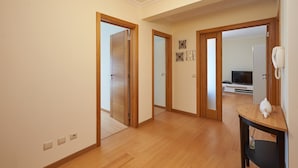 Een ruime hal met houten vloer, een houten deur en een klein tafeltje met een telefoon en een decoratief object.