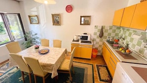 A compact kitchen with a dining area, featuring a microwave, sink, and a small table with chairs. - Apartman Hida (Jadranovo)