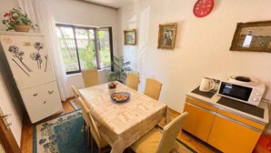 A compact kitchen with a microwave, a small refrigerator, and a dining area with a table and chairs. - Apartman Hida (Jadranovo)