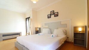 Una habitación de hotel moderna con una cama grande, mesitas de noche y una estantería de pared.