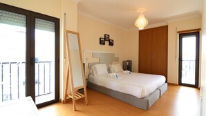Un dormitorio con cama, espejo de pie, armario y balcón.