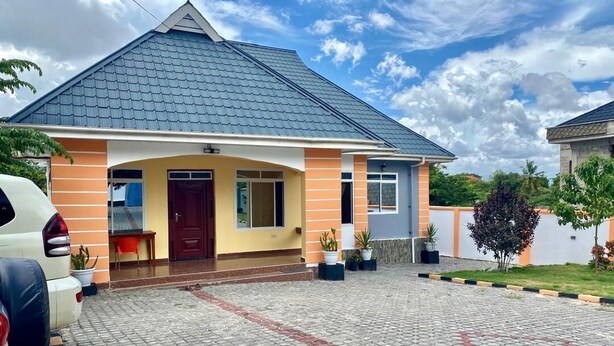 A house with a tiled roof, a porch, and a driveway.