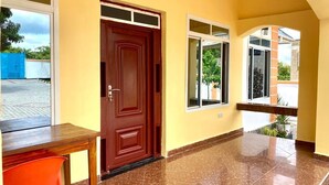 A hallway with a wooden door, a window, and a tiled floor.