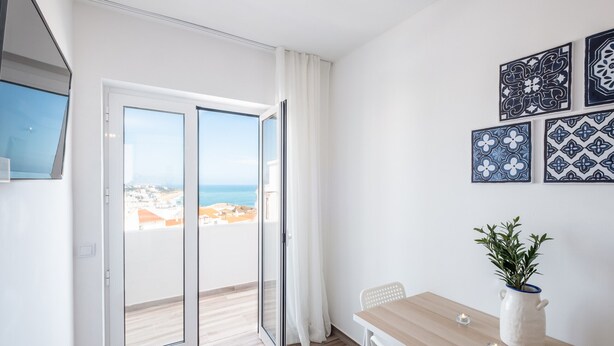 A modern room with a sliding glass door leading to a balcony with a city view.