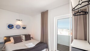 A modern bedroom with a large bed, a view of the city, and a balcony with a sliding door.