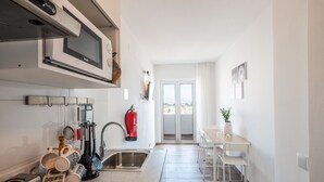 A modern kitchen with a built-in microwave, a sink, and a dining area with a table and chairs.