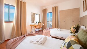 Ein Hotelzimmer mit zwei Betten, einem Schreibtisch, einem Stuhl und einem großen Fenster.