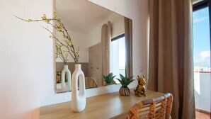 Ein Holztisch mit einem Spiegel, zwei weißen Vasen, einer ananasförmigen Vase und einer goldenen Statue.