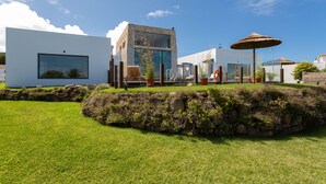 A modern house with a glass facade, a stone retaining wall, and a well-maintained lawn.