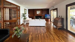 A spacious living room with a wooden floor, a white sofa, a TV, and a fireplace.