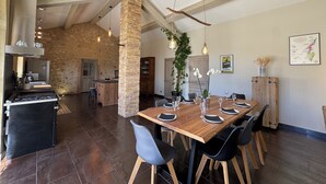 A spacious dining area with a wooden table set for six, surrounded by modern chairs. A brick column and hanging lights add to the rustic decor. - Mas provençal, garden, swimming pool and playground for children (Montboucher-sur-Jabron)