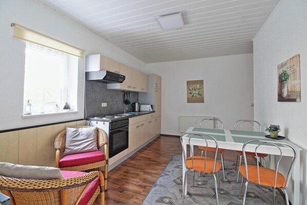 A compact kitchen with a stove, oven, and a dining area with a table and chairs.