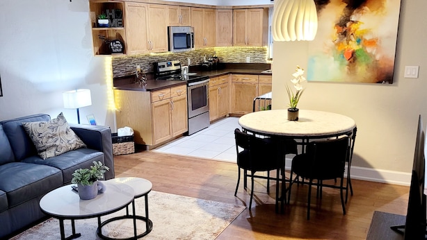 A modern living room with a sofa, coffee table, and a dining area with chairs. - Charming 2-bedroom, 2.5 bath townhome in Gainesville - WiFi, AC, parking & more! (Gainesville)