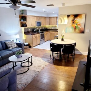 A modern living room with a sofa, coffee table, and a dining area with chairs. - Charming 2-bedroom, 2.5 bath townhome in Gainesville - WiFi, AC, parking & more! (Gainesville)