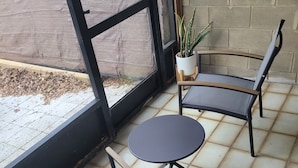 A covered patio area with two chairs and a small table, a potted plant, and a view of the outside. - Charming 2-bedroom, 2.5 bath townhome in Gainesville - WiFi, AC, parking & more! (Gainesville)