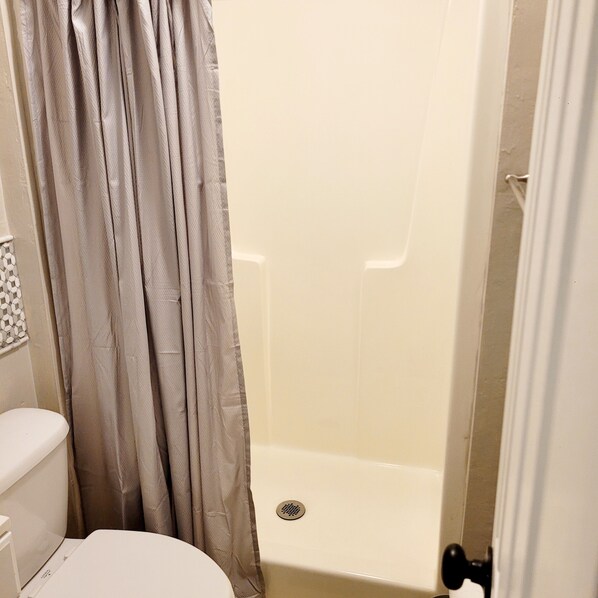 A bathroom with a toilet, a shower stall, and a curtain. - Charming 2-bedroom, 2.5 bath townhome in Gainesville - WiFi, AC, parking & more! (Gainesville)