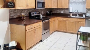 A kitchen with wooden cabinets, a microwave, a stove, and a sink. - Charming 2-bedroom, 2.5 bath townhome in Gainesville - WiFi, AC, parking & more! (Gainesville)