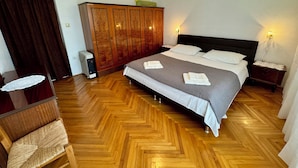A bedroom with a large bed, wooden wardrobe, bedside lamps, and a radiator. - Apartment Kristina 2 (Jadranovo)