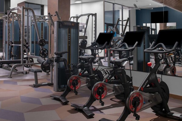 Un gimnasio con bicicletas estáticas, máquinas de pesas y pesas libres.