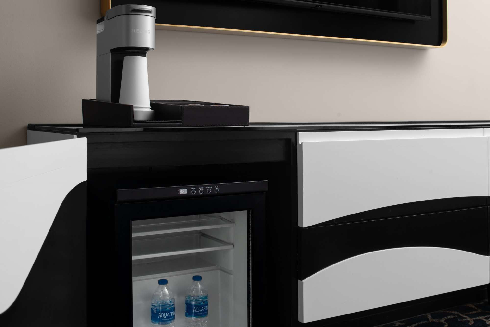 Een minibar met een waterdispenser en een kleine koelkast.