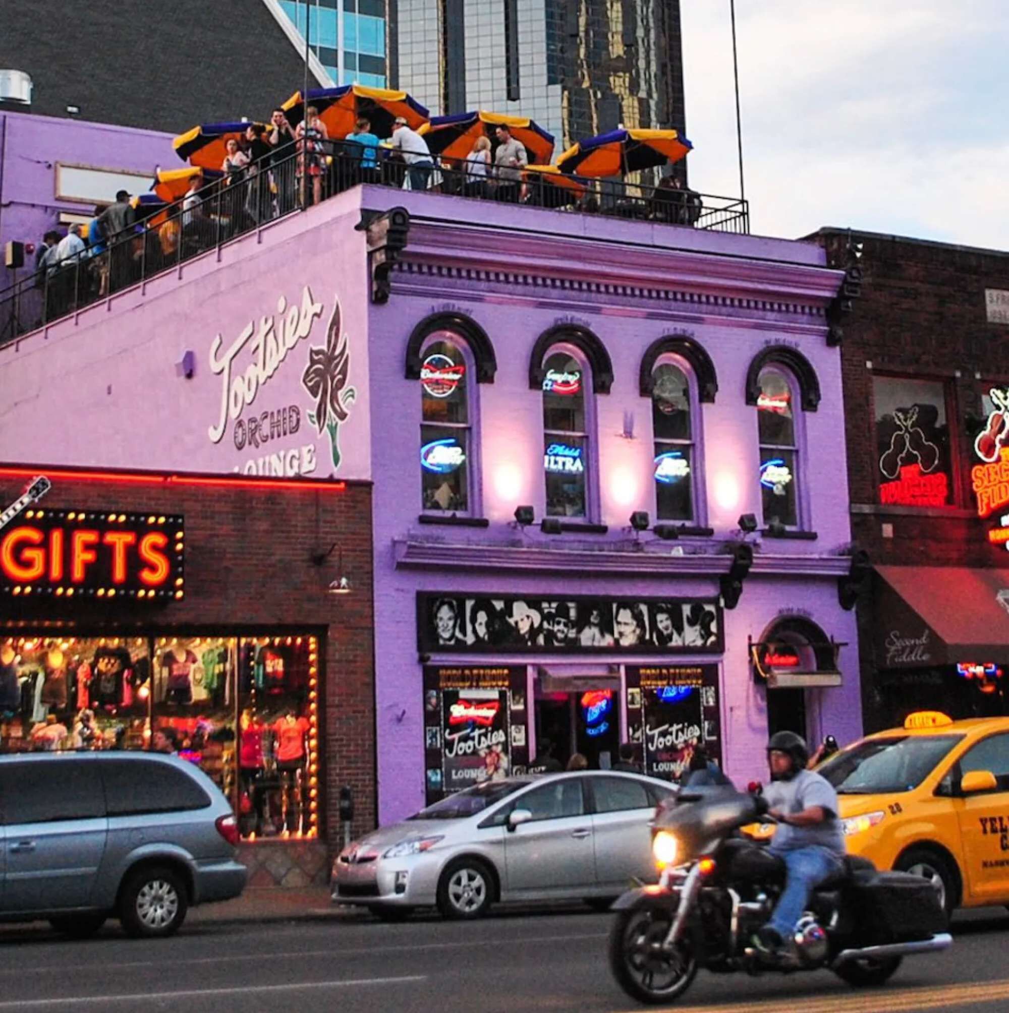 Un bâtiment à deux étages, avec une façade violette, des devantures de magasins au rez-de-chaussée et une rangée de parapluies à l’étage supérieur.
