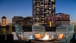 Une terrasse sur le toit, avec deux fauteuils en osier et un foyer central.