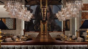 Un restaurant doté d’un long comptoir, de murs recouverts de miroirs et d’un lustre central.